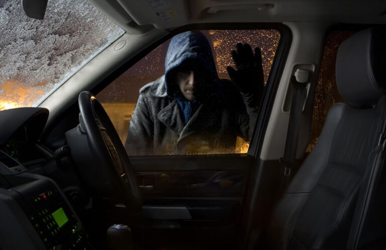 An image of somebody trying to break into a car at night
